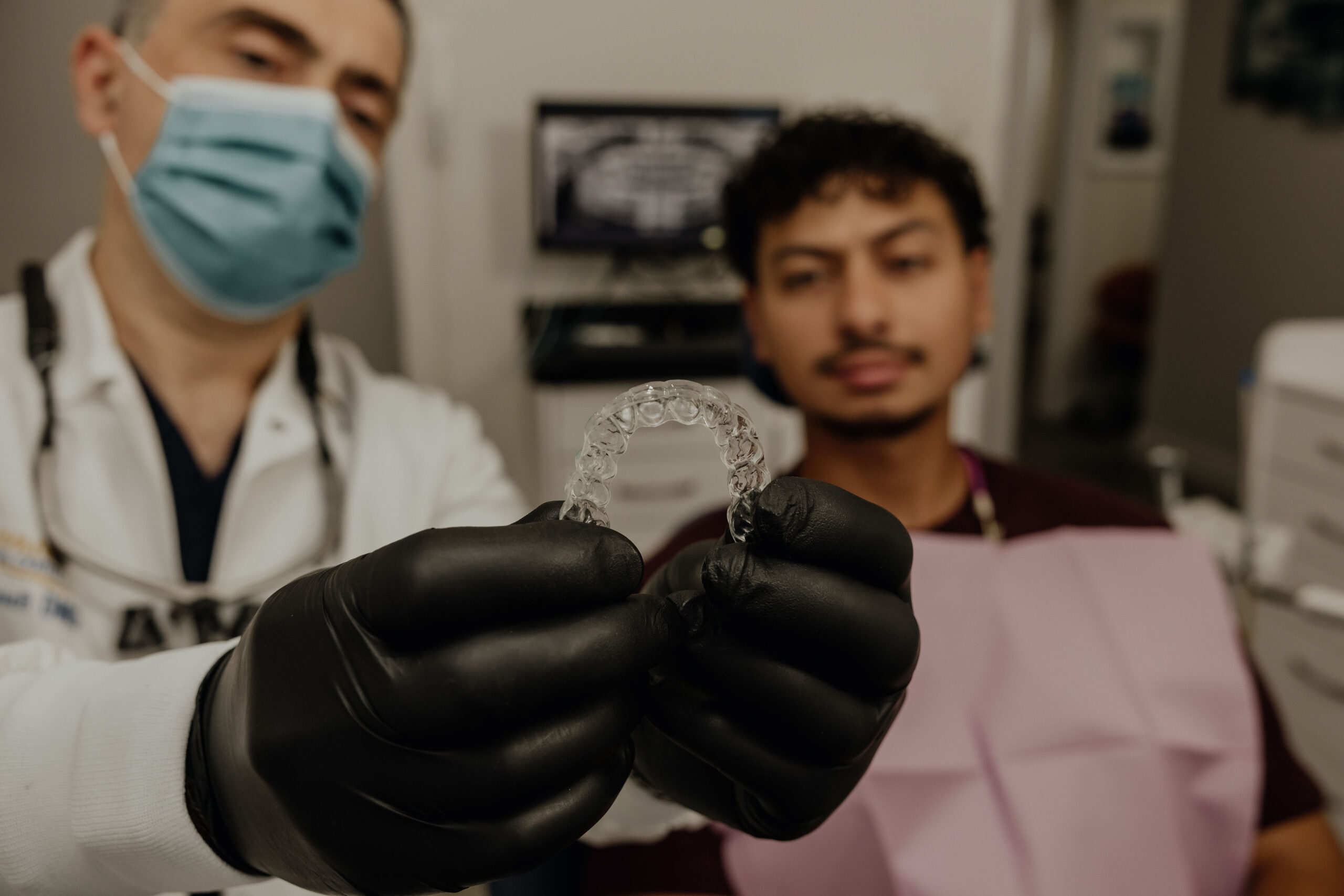 Dentist showing Invisalign clear aligners to an adult patient during consultation at Norwalk dental office.